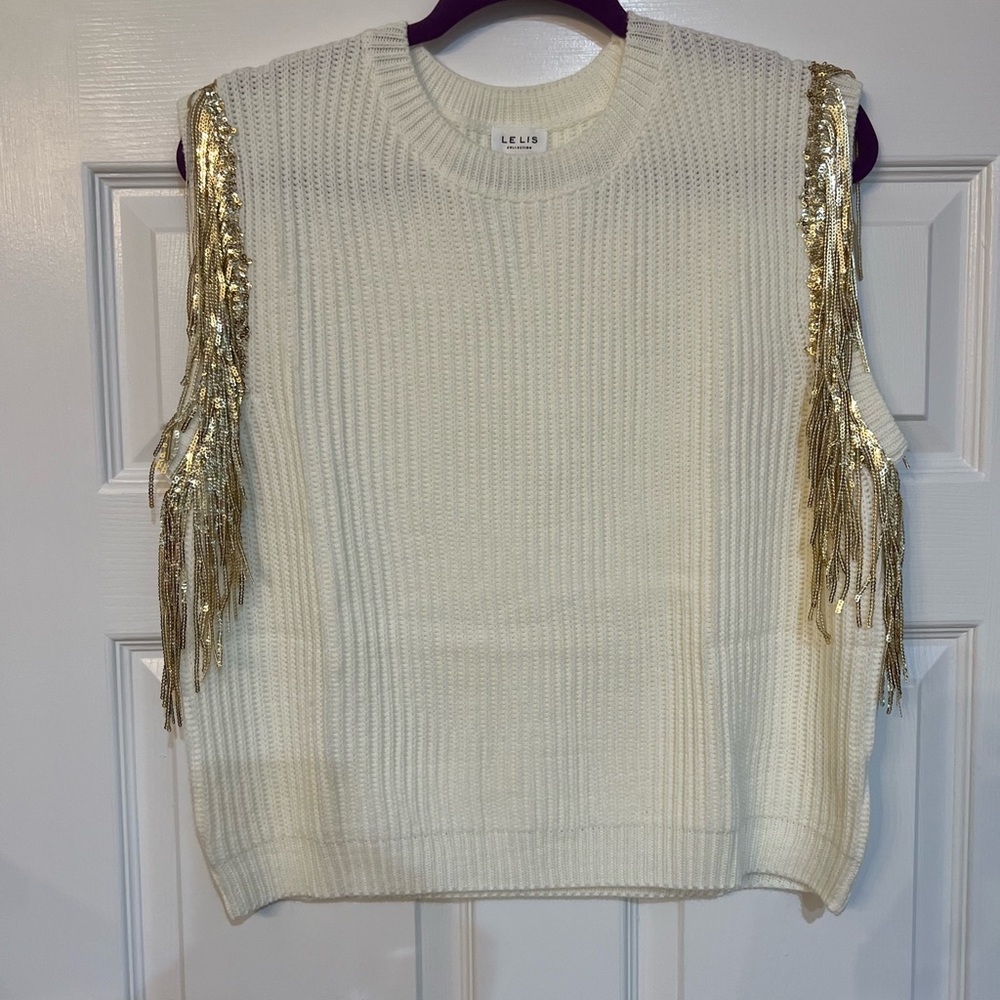 Sleeveless sweater with gold fringe.
